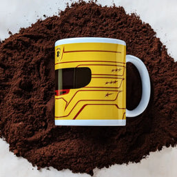 Lewis Hamilton Ferrari 2025 F1 helmet mug resting on a bed of ground coffee, showcasing the bold yellow design with red accents.